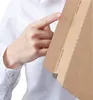 A person's hand is pointing to the edge of a brown cardboard envelope. Anteprima dell’immagine prodotto