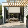 An outdoor dining area with a retractable awning over a table and chairs, next to a modern house. Náhled obrázku produktu