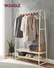 A clothing rack with clothes, bags, and shoes, set against a textured gray wall. Voir les images du produit
