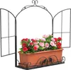 A black metal window frame with an attached brown planter filled with red and pink artificial flowers, set against a white background. Produktbild-Vorschau