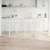 A white folding pet gate is set up in a kitchen area in front of cabinets. Podgląd zdjęcia produktu