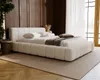 A modern bedroom with a large, plush boucle bed as the focal point, bathed in natural light from a large window. Náhľad obrázku produktu