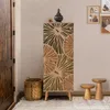 A tall, narrow cabinet with a decorative pattern stands in a room next to a wooden door and a basket. Two small wooden stools are placed in front of the cabinet. Anteprima dell’immagine prodotto