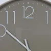 A close-up view of a taupe clock face with white numbers and hands. Produktbild-Vorschau