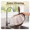 A hand is filling a beige and brown electric kettle with water from a faucet. Podgląd zdjęcia produktu