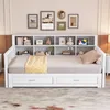 A white daybed with a built-in bookshelf headboard, decorated with various items and artwork, set in a bedroom. Náhled obrázku produktu