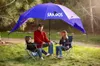 A family is sitting under a large blue and purple umbrella on a grassy area. Voir les images du produit