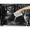 A person is pouring a white powder from a packet into the bottom of a dishwasher. Produktbild-Vorschau