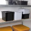 Storage bins are neatly arranged on shelves in what appears to be a storage area or garage. Voir les images du produit
