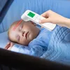 A hand holding a digital thermometer to a sleeping baby's forehead. Produktbild-Vorschau