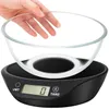 A hand is holding a glass bowl over a black digital kitchen scale. Produktbild-Vorschau