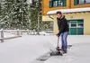 A man is using a snow blower to clear snow from a driveway in front of a house. Produktbild-Vorschau