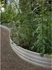 A curved metal garden edging separates a gravel path from a planted area with green foliage. Produktbild-Vorschau