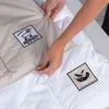 Hands holding a folded duvet, showing labels. Podgląd zdjęcia produktu