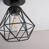 A close-up shot of a black geometric pendant light fixture with a visible filament bulb. Produktbild-Vorschau