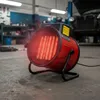 A red electric heater is placed on the floor of a garage, with a car in the background. Náhled obrázku produktu