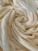 A close-up shot of a soft, textured fabric, likely a blanket or sheet, folded and swirled to create a sense of depth and comfort. Produktbild-Vorschau