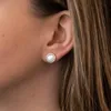 Seitliche Ansicht von einem runden Ohrstecker mit rosafarbenem Perlmutt und Zirkonia-Fassung am Ohr einer Frau, dezent und elegant. Produktbild-Vorschau