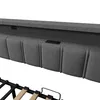 Close-up view of a gray upholstered headboard with integrated charging ports and a bed frame. Náhled obrázku produktu