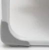 Close-up of the corner of a white baby cradle with a gray plastic protective cover. Produktbild-Vorschau