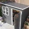 A dark gray garden shed with an open door, revealing shelves stocked with tools and containers. The shed has a window and is situated outdoors on a paved patio with potted plants nearby. Produktbild-Vorschau