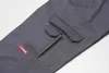 A close-up view of the cargo pocket and a red brand tag on a pair of gray pants. Produktbild-Vorschau