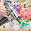 A hand holding a portable vacuum cleaner with various balloon decorations in the background. Produktbild-Vorschau