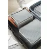 Hands are placing a set of gray polka dot packing cubes into an open suitcase. Voir les images du produit