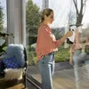 A woman is cleaning a large window in a sunlit room. Náhľad obrázku produktu