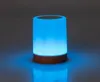 A blue illuminated lamp with a wooden base on a reflective surface. Voir les images du produit