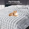 A ginger cat is lying on a light gray, plush blanket with a textured pattern. Náhled obrázku produktu