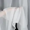A hand holding a sheer white curtain. Produktbild-Vorschau