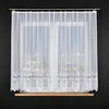 A white lace curtain is hung on a window with a city view at night visible through it. Náhled obrázku produktu