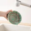 A hand is holding a decorative bowl under a faucet in a sink, with water running into it. Produktbild-Vorschau