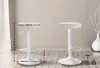 Two white bar stools are shown in a room with light-colored walls and wooden flooring. One stool has dimensions indicated by measurement lines and text. Podgląd zdjęcia produktu