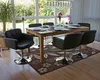 A dining room scene with a wooden table and chairs set for a meal, with a large window overlooking a garden. Produktbild-Vorschau