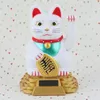 A white Maneki-neko (lucky cat) figurine with a gold coin and a red collar, sitting on a gold base. Produktbild-Vorschau