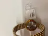 Close-up of the back of a gold-colored watch with a tag attached. Produktbild-Vorschau