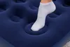 A close-up shot of a person's foot in a white sock pressing down on a dark blue inflatable mattress. Náhľad obrázku produktu