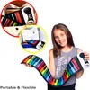 A girl is holding a flexible rainbow piano keyboard, with inset images showing the product in its packaging and a bag. Produktbild-Vorschau