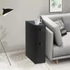 A black narrow storage cabinet with two drawers is placed next to a gray sofa in a living room setting. Náhľad obrázku produktu
