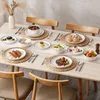 Weißes Porzellanset und silbernes Besteck auf hellem Holztisch Voir les images du produit