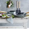 A collection of cookware and ingredients arranged on a rustic wooden table against a textured gray wall. Náhled obrázku produktu