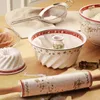 A collection of Christmas-themed baking items, including bundt pans, a rolling pin, a sieve, and bowls, arranged on a wooden surface. Náhled obrázku produktu