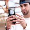 A man is holding a smartphone with a protective case. Produktbild-Vorschau