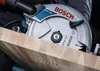 A close-up shot of a circular saw blade cutting into a wooden surface. Voir les images du produit