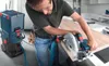 A man is using a circular saw to cut a piece of wood, with a Bosch vacuum cleaner attached. Náhled obrázku produktu