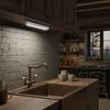 A kitchen scene with a sink, faucet, and cabinets, illuminated by an under-cabinet LED light. Produktbild-Vorschau