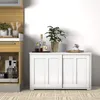 A white sideboard with sliding doors is shown in a room with a wooden cabinet to the left and a tiled floor. Náhľad obrázku produktu