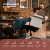 A man is relaxing in a pink office chair in a room with a brick wall and shelves. Podgląd zdjęcia produktu
